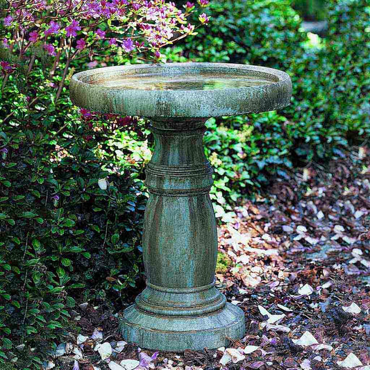 Decorative garden birdbath with a textured surface in a garden setting.