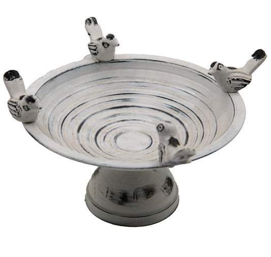 A silver metal tabletop birdbath with multiple bird figurines perched on the edge.