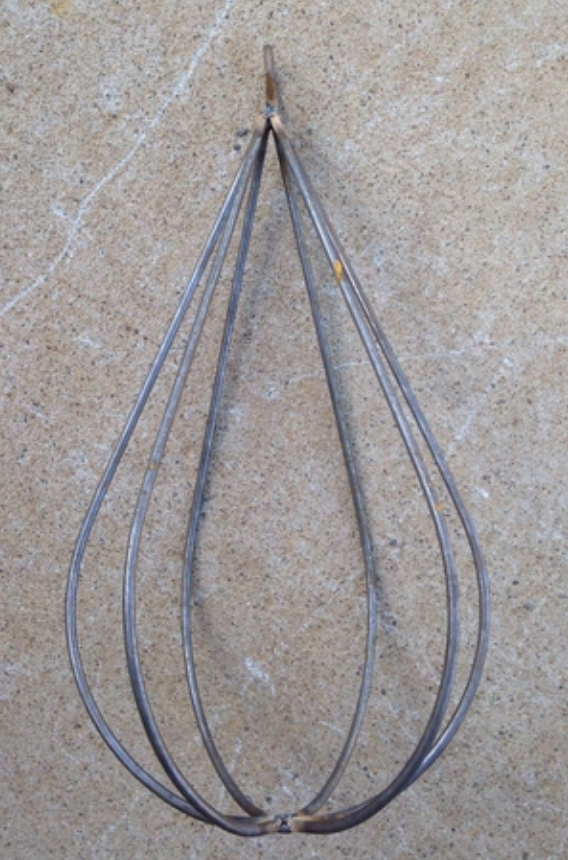 A solid steel decorative trellis designed to resemble a raindrop, with multiple slender branches radiating from a central point, set against a concrete background.