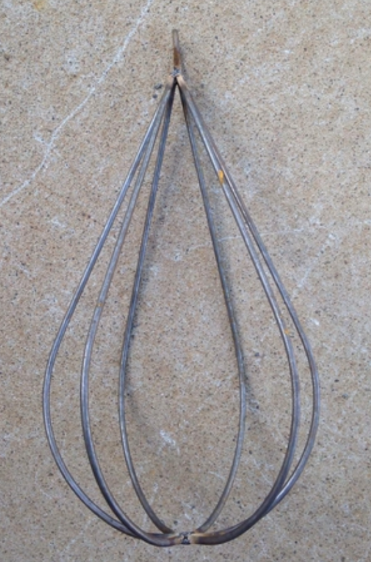 A solid steel decorative trellis designed to resemble a raindrop, with multiple slender branches radiating from a central point, set against a concrete background.