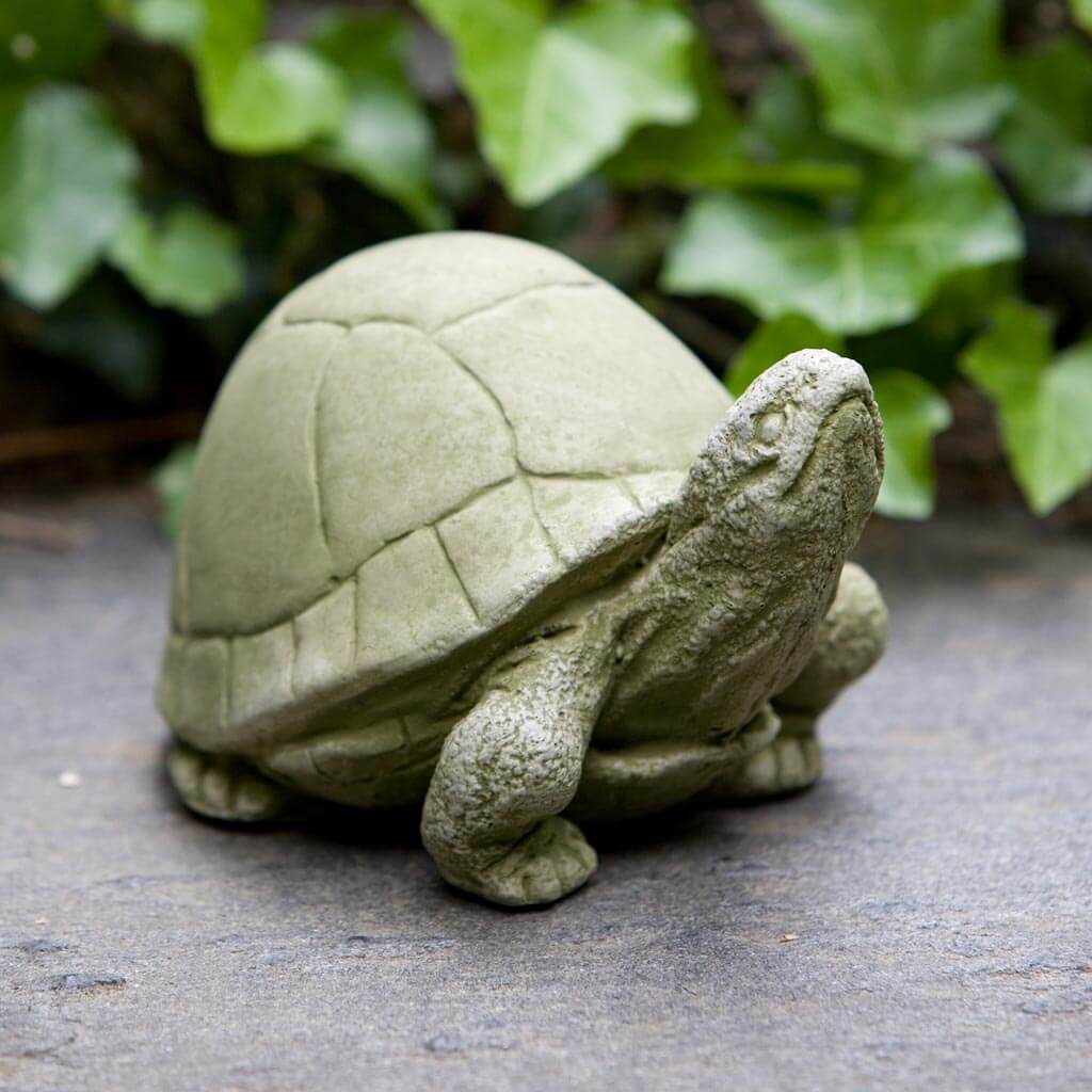 Stone turtle sculpture on a stone surface with greenery in the background